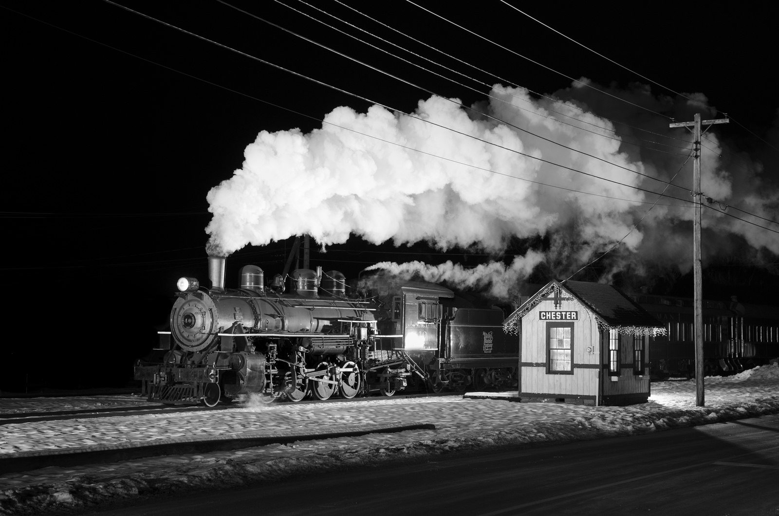 steam train passing a small passenger shelter